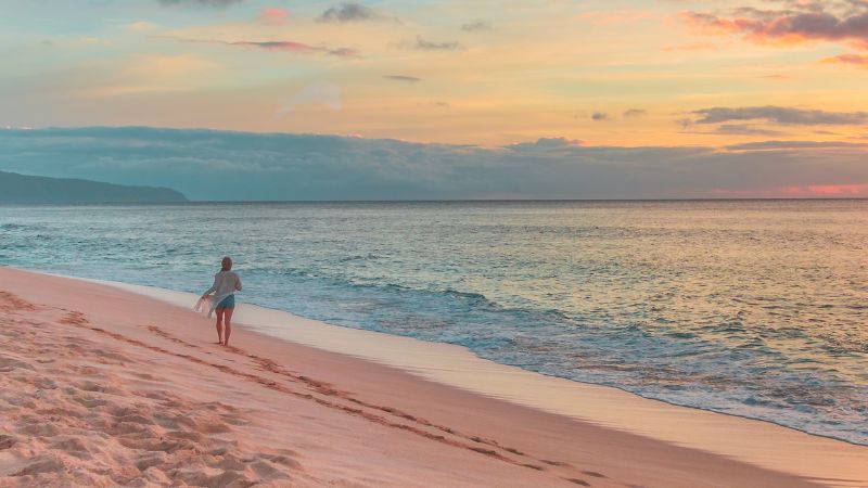 Woman walking on the beach at sunrise